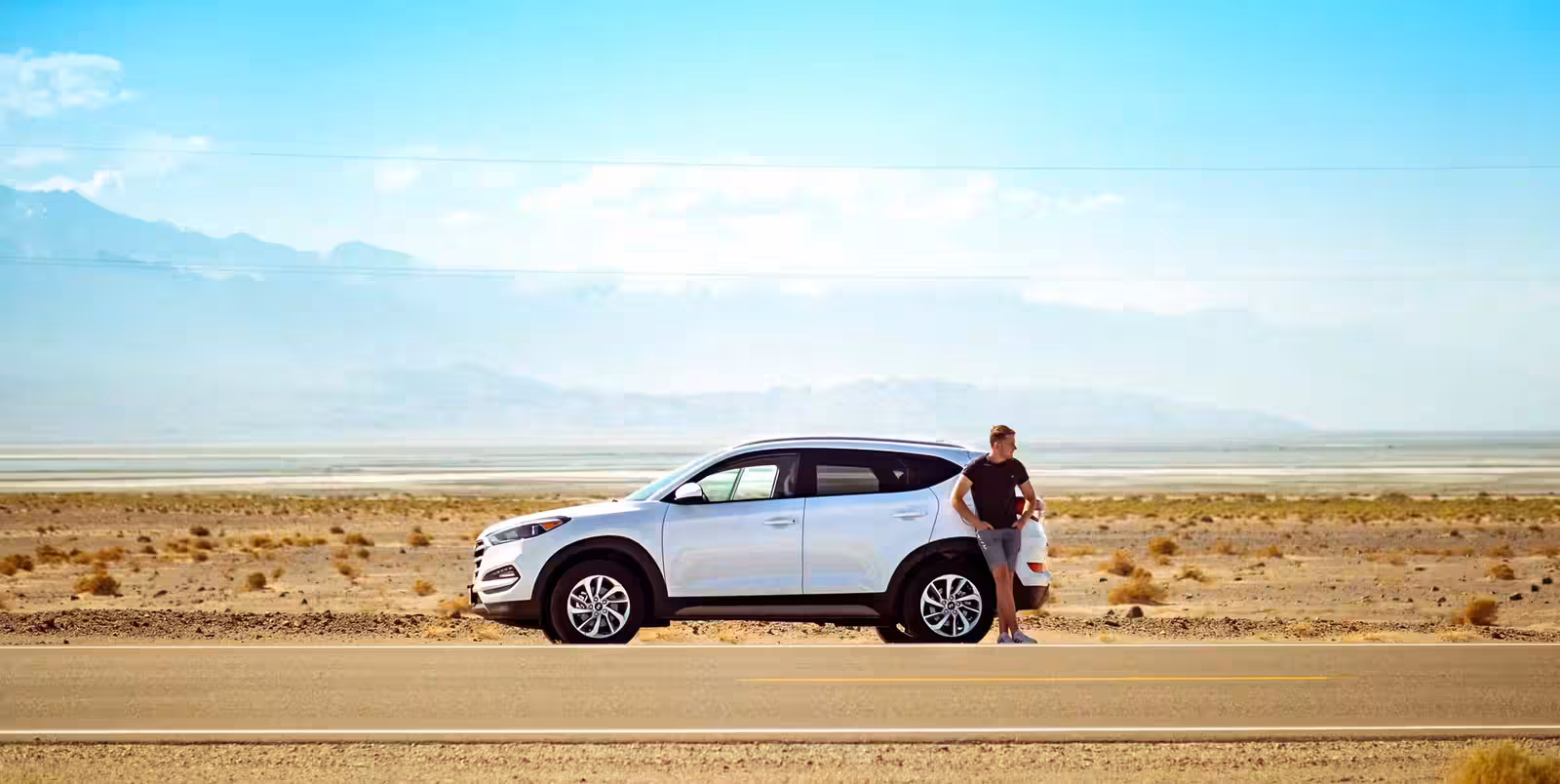 Driver leaning against a car in the California desert